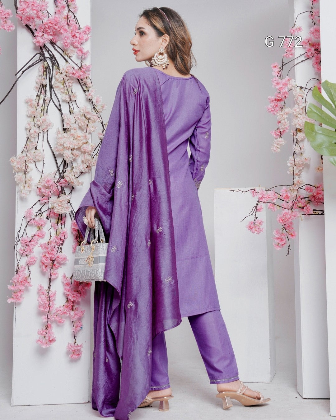 Woman wearing a purple outfit with floral decorations on a white background