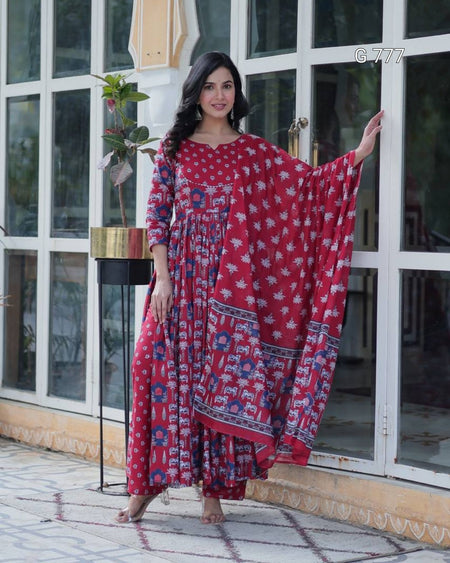 Woman wearing a red and blue patterned dress standing in front of a glass door.