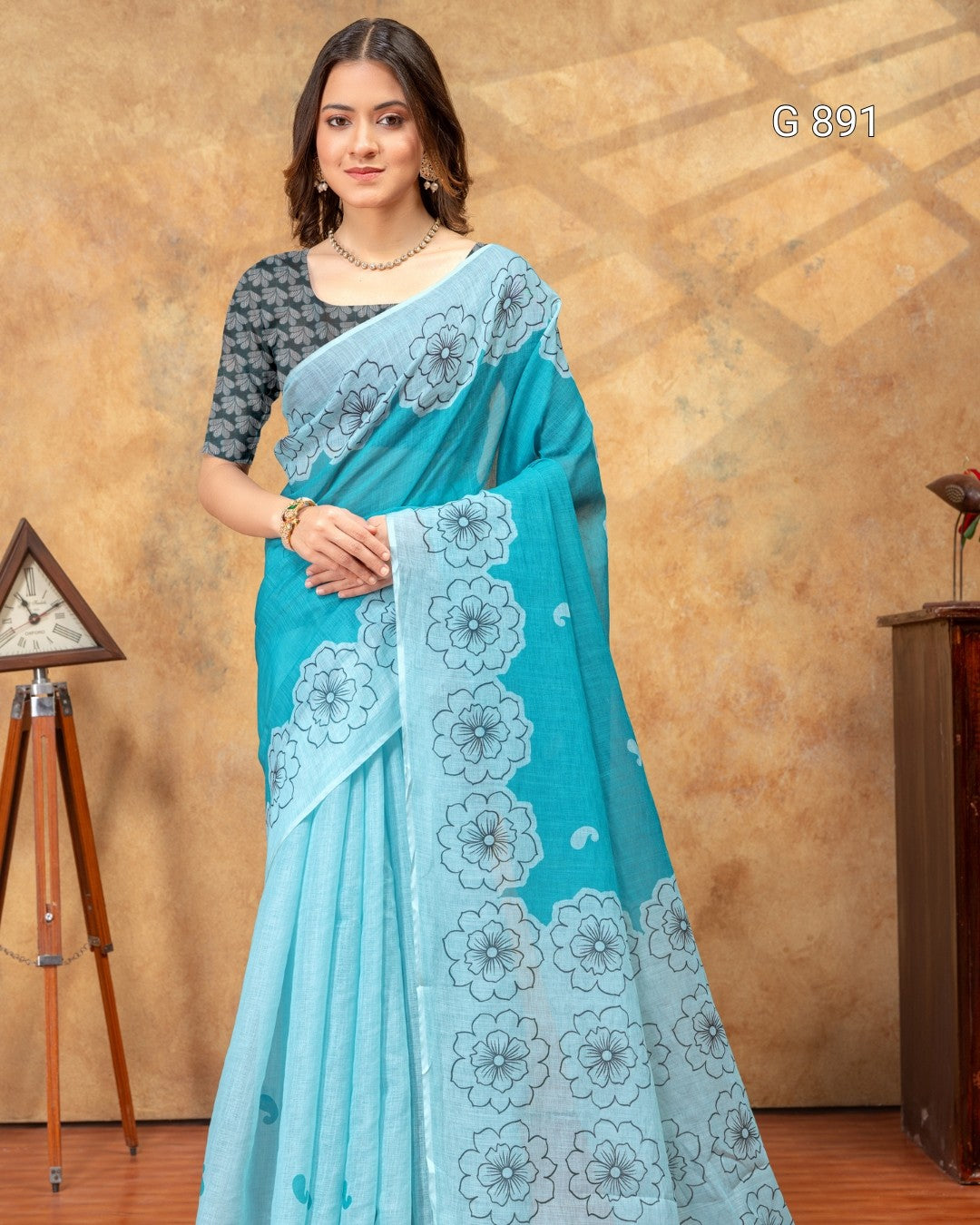 Woman wearing a blue saree with white floral patterns against a beige background