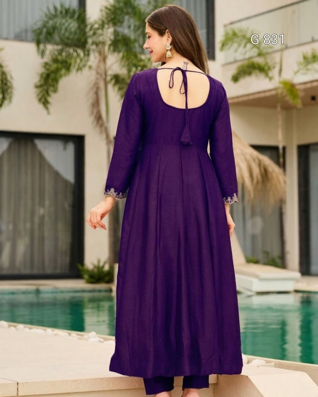 Woman wearing a purple dress with a backless design by a poolside.