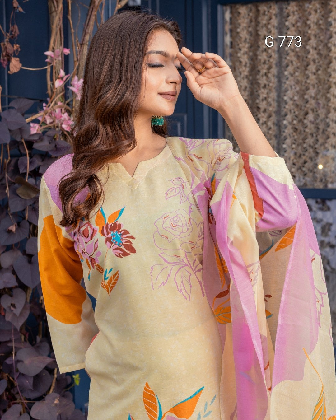 Woman wearing a floral saree with a colorful blouse, standing outdoors.