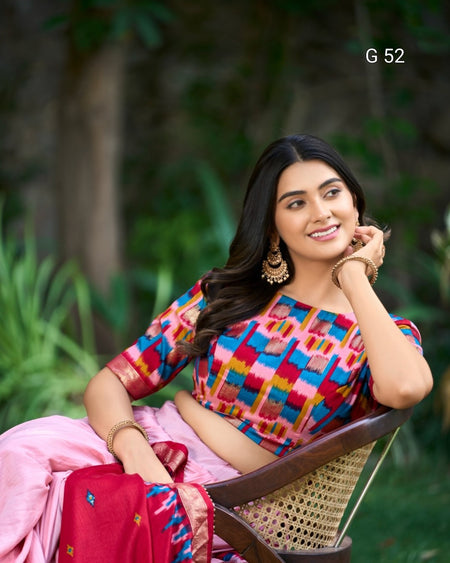 Woman in a colorful traditional outfit sitting outdoors with greenery in the background
