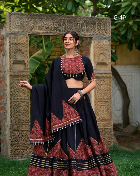 Woman in traditional outfit standing in front of an ornate stone archway.