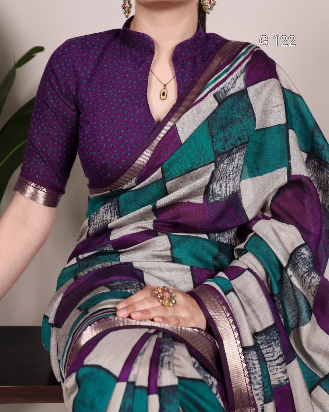 Woman wearing a colorful saree with a patterned blouse against a neutral background