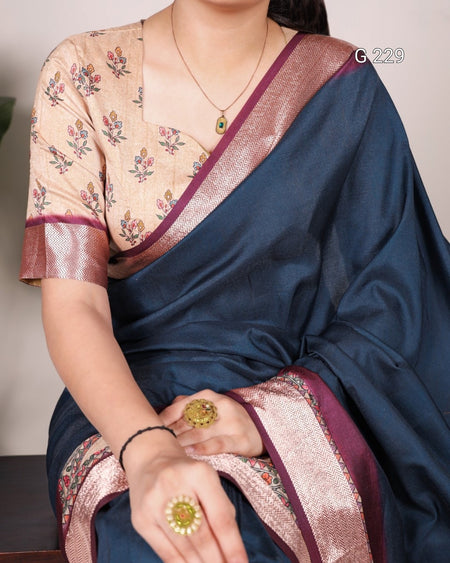 Person wearing a blue saree with floral blouse, sitting indoors.