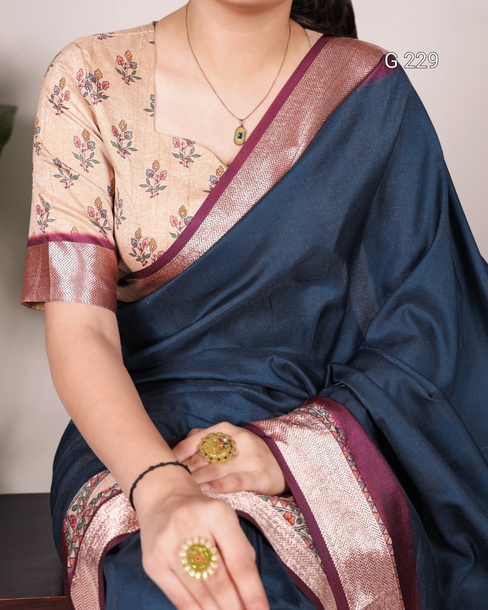 Person wearing a blue saree with floral blouse, sitting indoors.