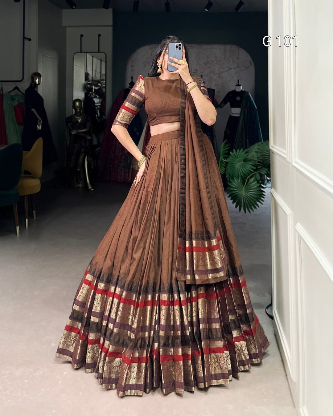 Person wearing a traditional brown and red outfit with a matching dupatta in a room.