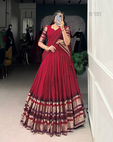 Person wearing a red saree with gold patterns in a room setting.