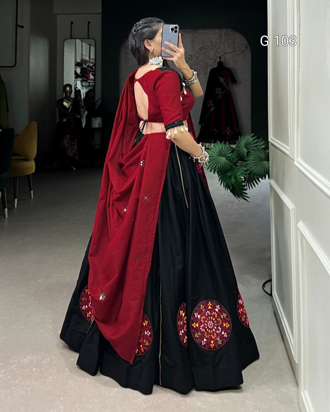 Woman in a red and black saree with floral patterns, standing in a room.