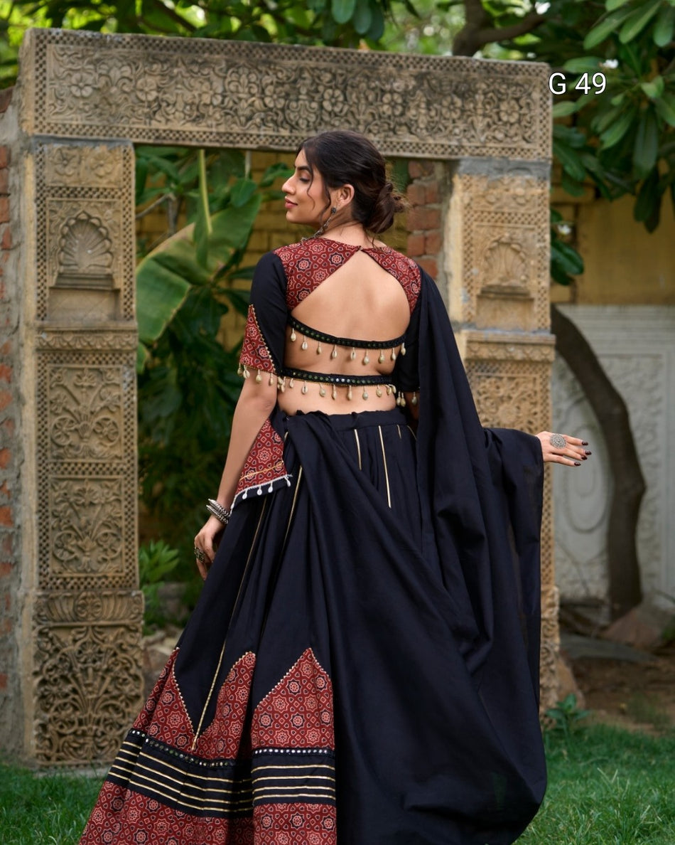 Woman in a traditional outfit standing in front of an ornate stone archway.