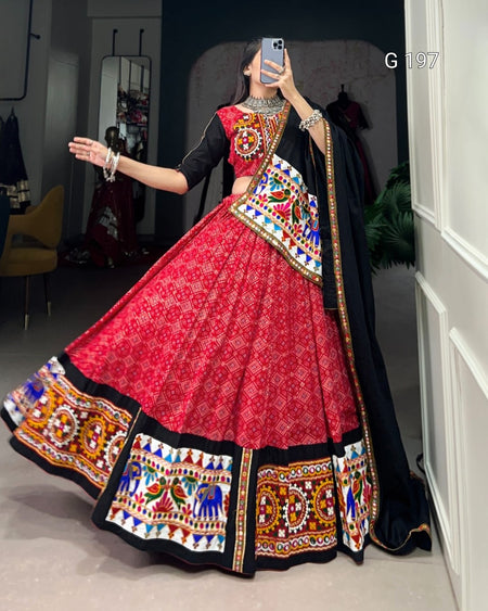 Person wearing a traditional red and black embroidered outfit in a room.