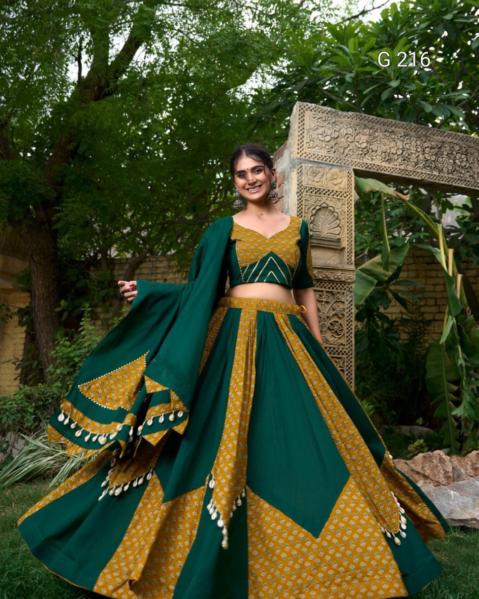 Woman in a green and yellow traditional outfit standing outdoors with decorative background