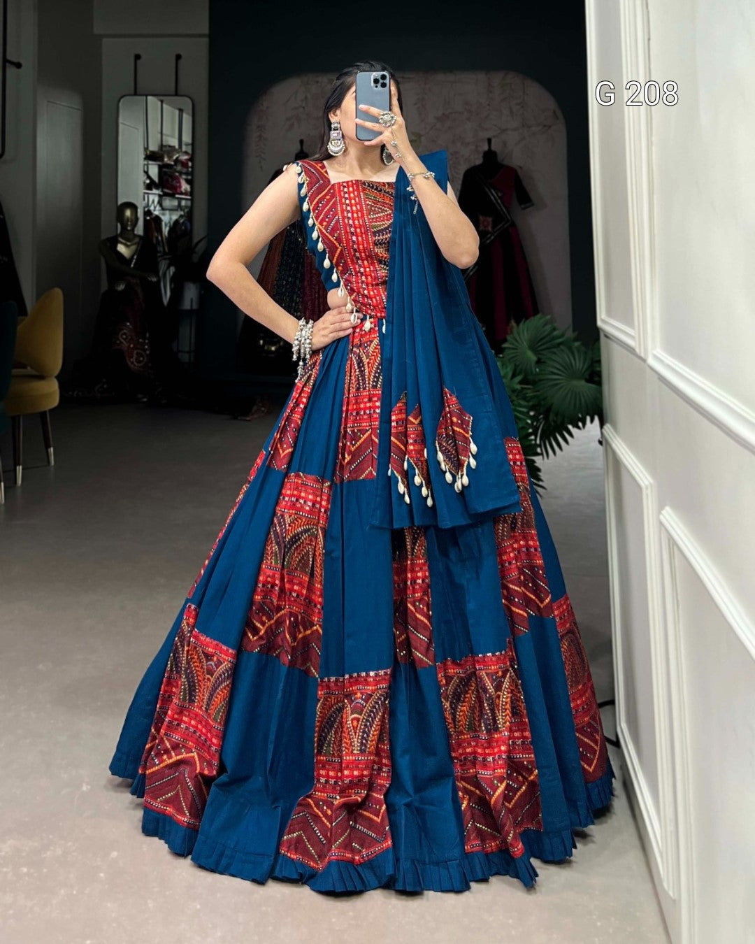 Woman wearing a blue and red patterned dress taking a mirror selfie.