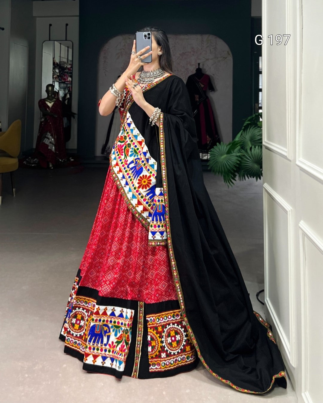 Person wearing a traditional black and red saree with colorful patterns indoors.