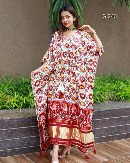 Woman wearing a colorful floral and patterned dress standing outdoors.