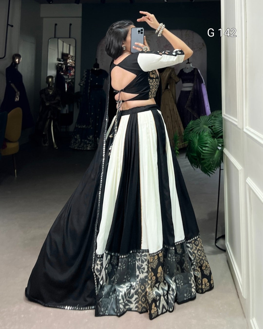 Person wearing a black and white patterned outfit in a room with mirrors and clothing.