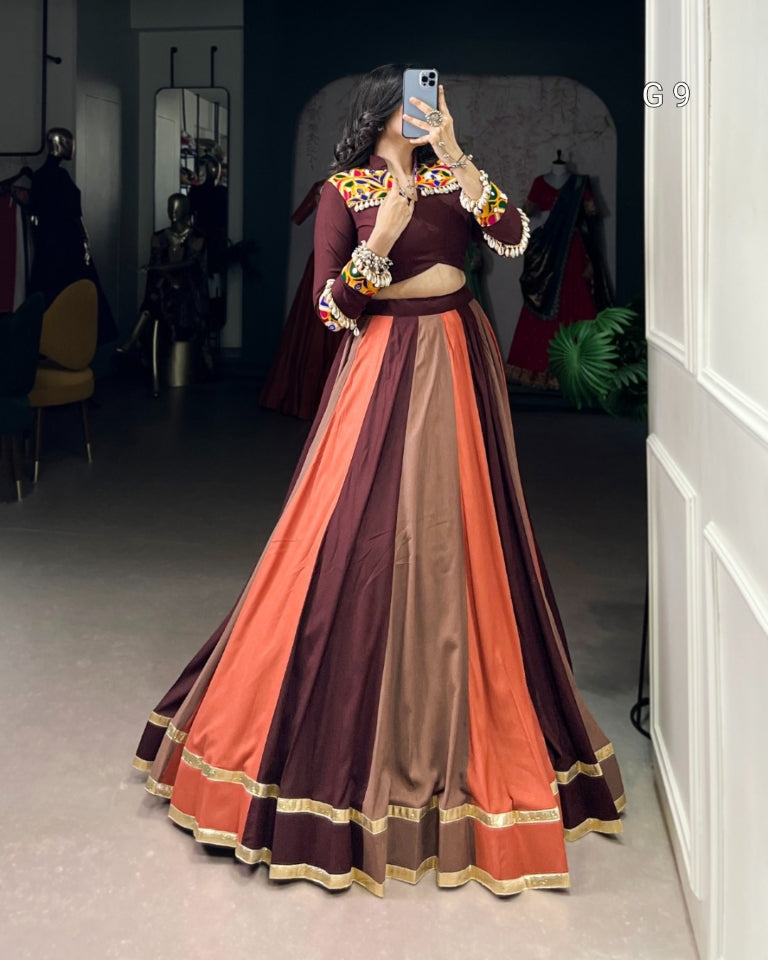 Person wearing a colorful traditional outfit with a patterned top and multicolored skirt in a room.