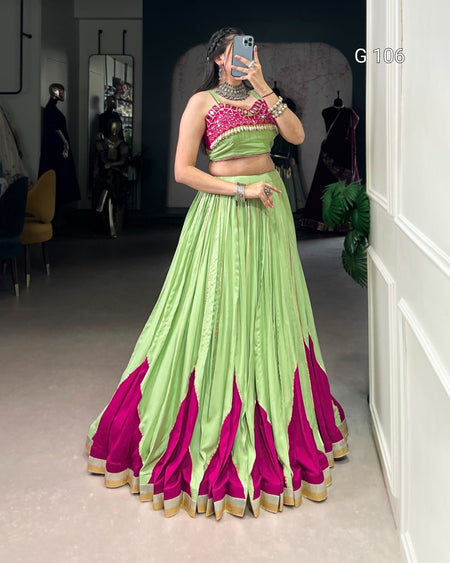 Person wearing a green and pink traditional outfit in a room.