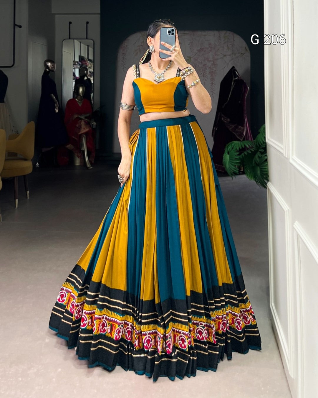 Woman wearing a yellow and blue traditional outfit with intricate patterns indoors.