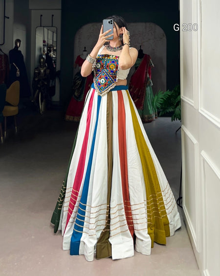 Person wearing a colorful traditional outfit with a multicolored skirt in a room.