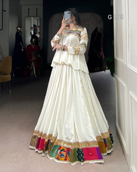Person wearing a white traditional outfit with colorful patterns in a room.
