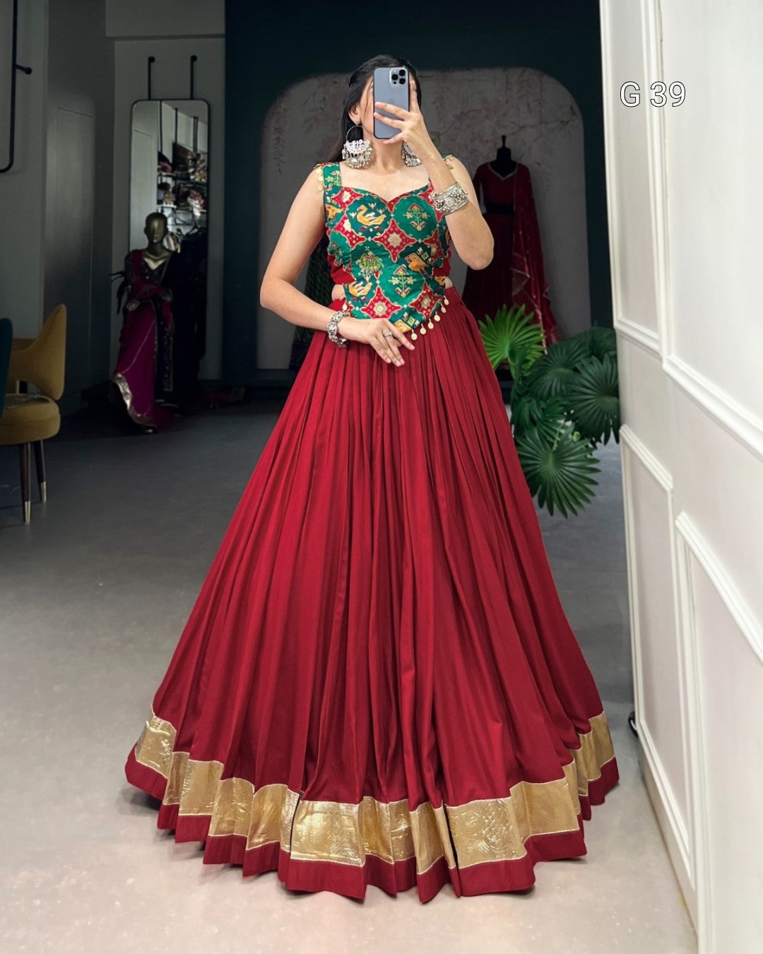 Woman wearing a red and green traditional outfit in a room with mirrors and decor.
