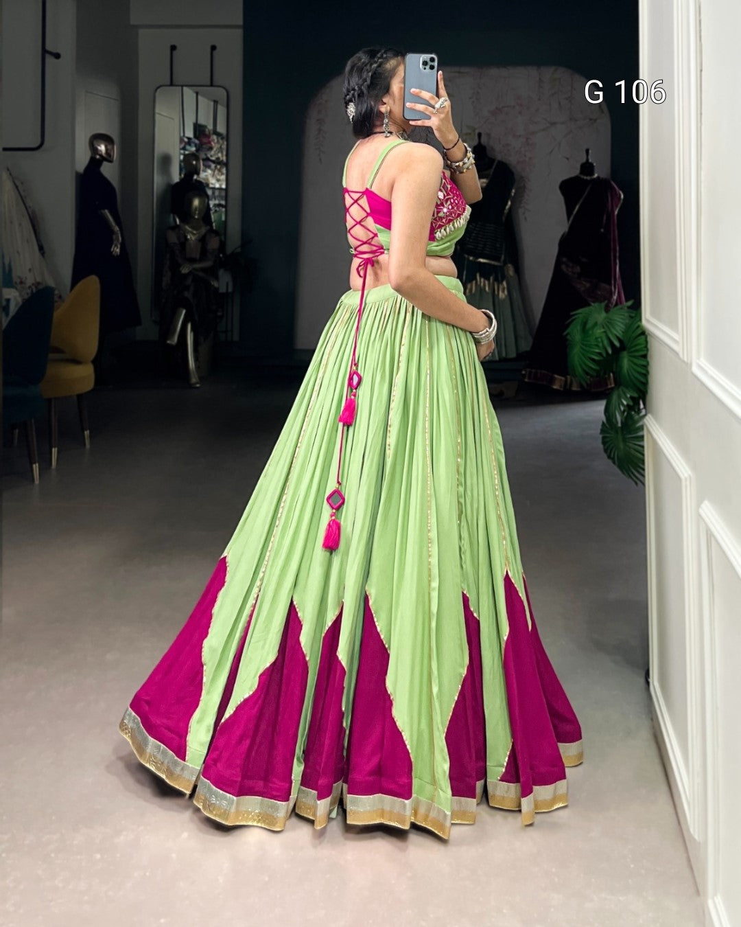 Person wearing a green and pink traditional outfit taking a mirror selfie.