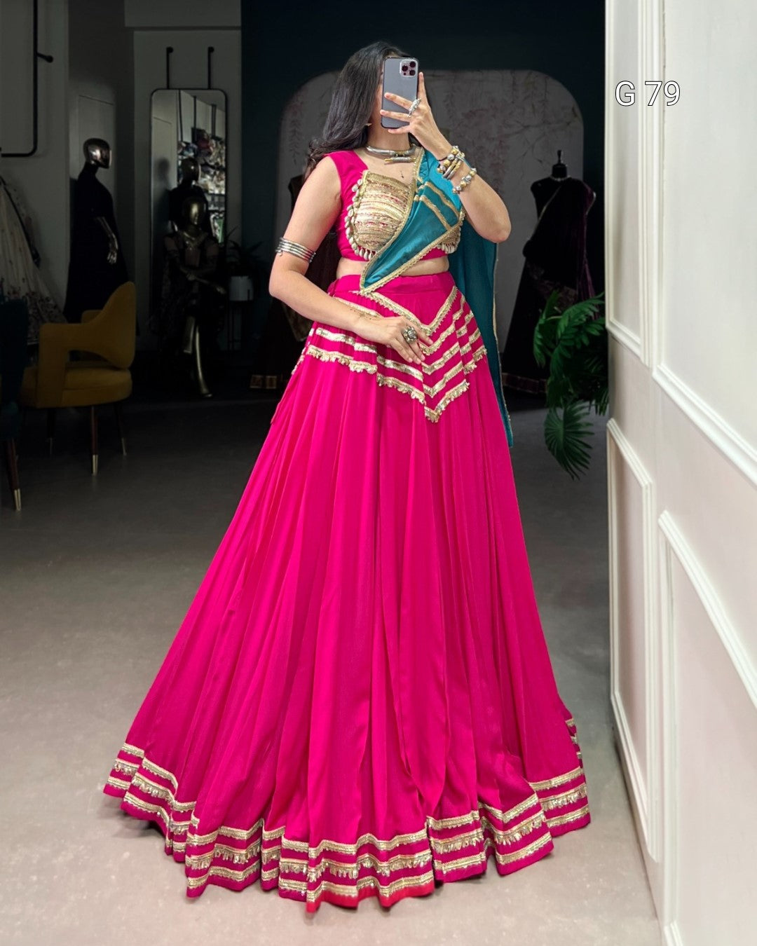 Woman wearing a bright pink traditional outfit with gold details in a room.