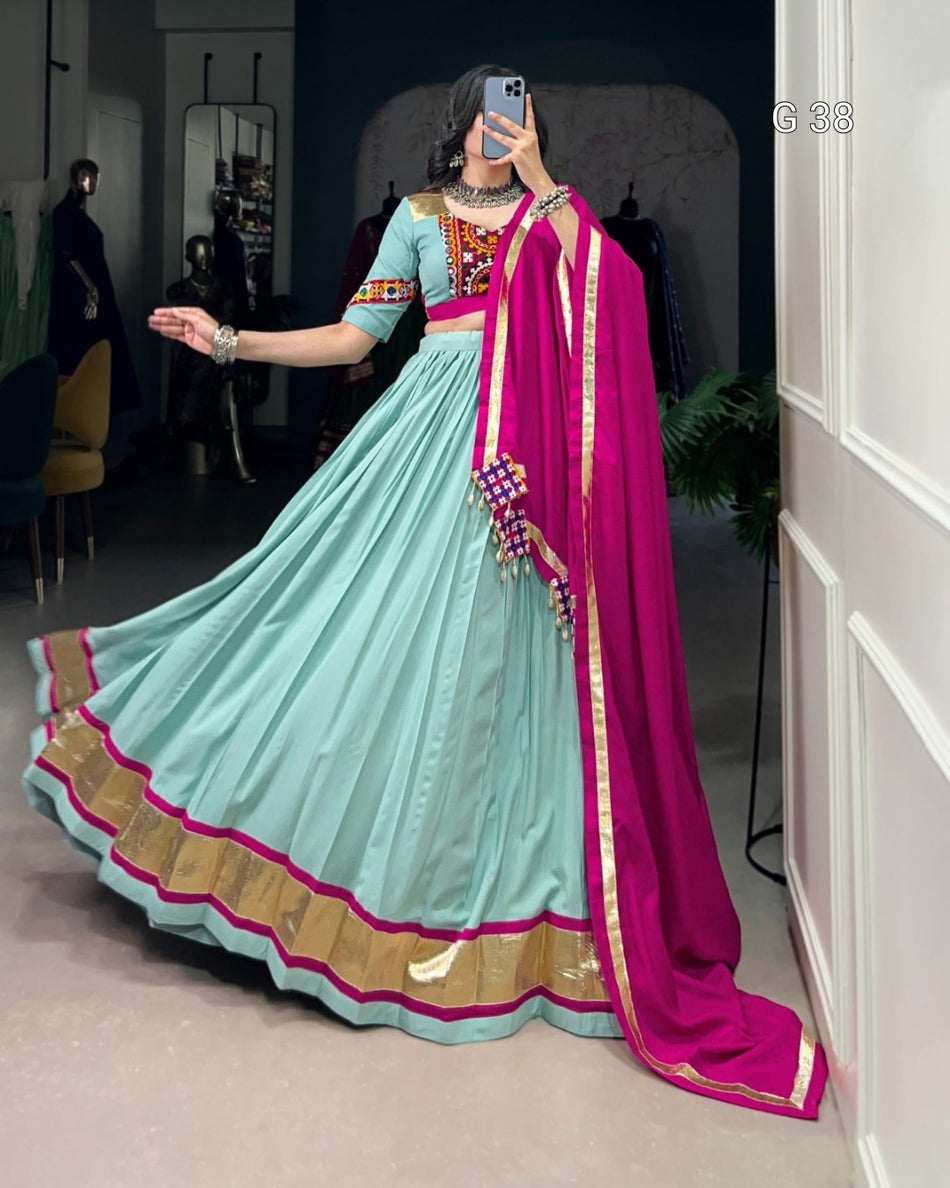 Person wearing a light blue saree with pink border indoors.