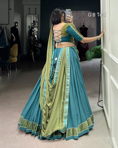 Woman wearing a blue and green saree taking a mirror selfie.