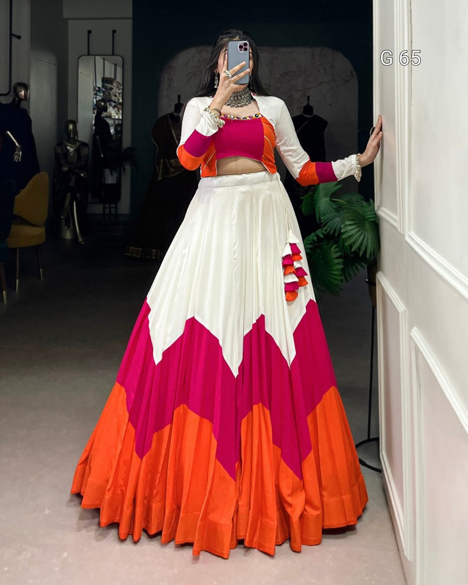 Woman taking a mirror selfie wearing a colorful traditional outfit with a white, pink, and orange design.