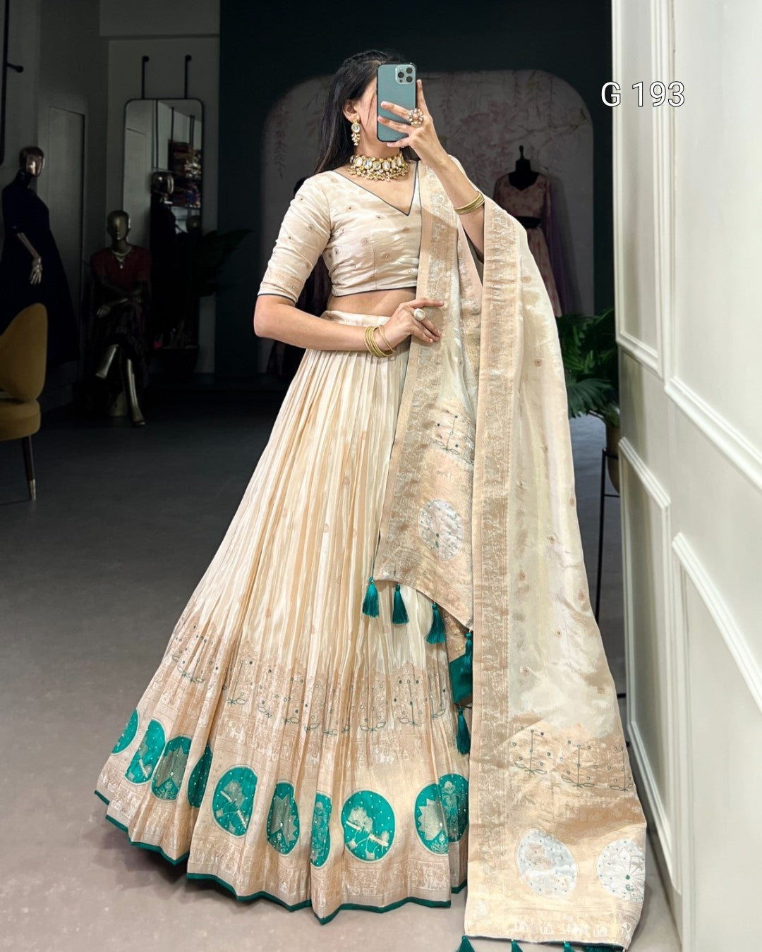 Woman wearing a traditional outfit with a beige and green design, standing in a room.