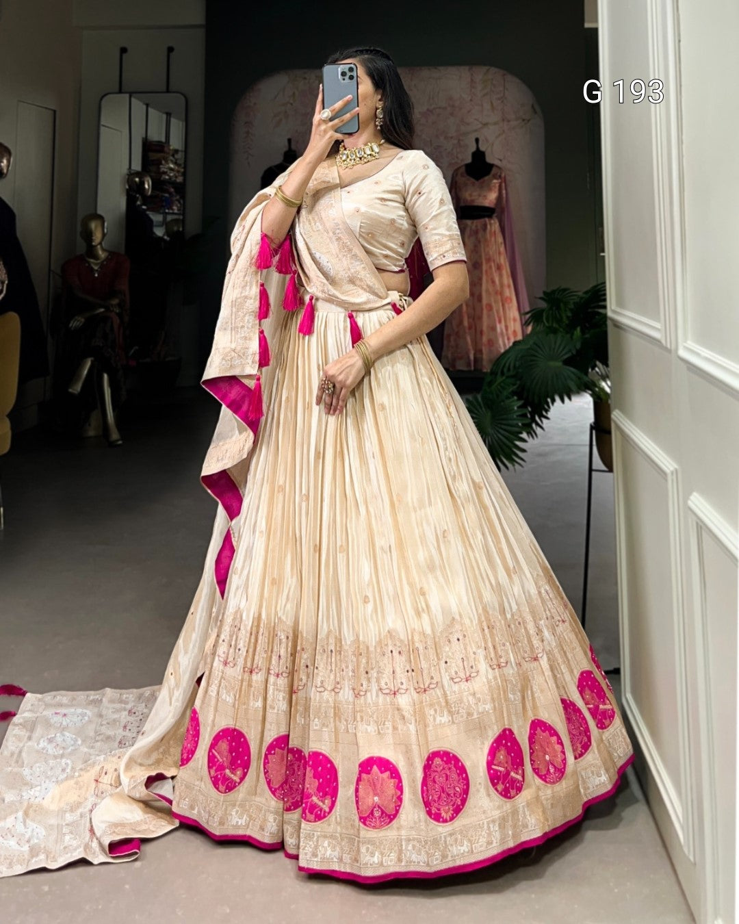 Woman wearing a traditional outfit with pink and beige design in a room.