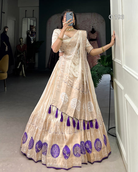 Woman wearing a traditional outfit with a beige and purple design in a room.