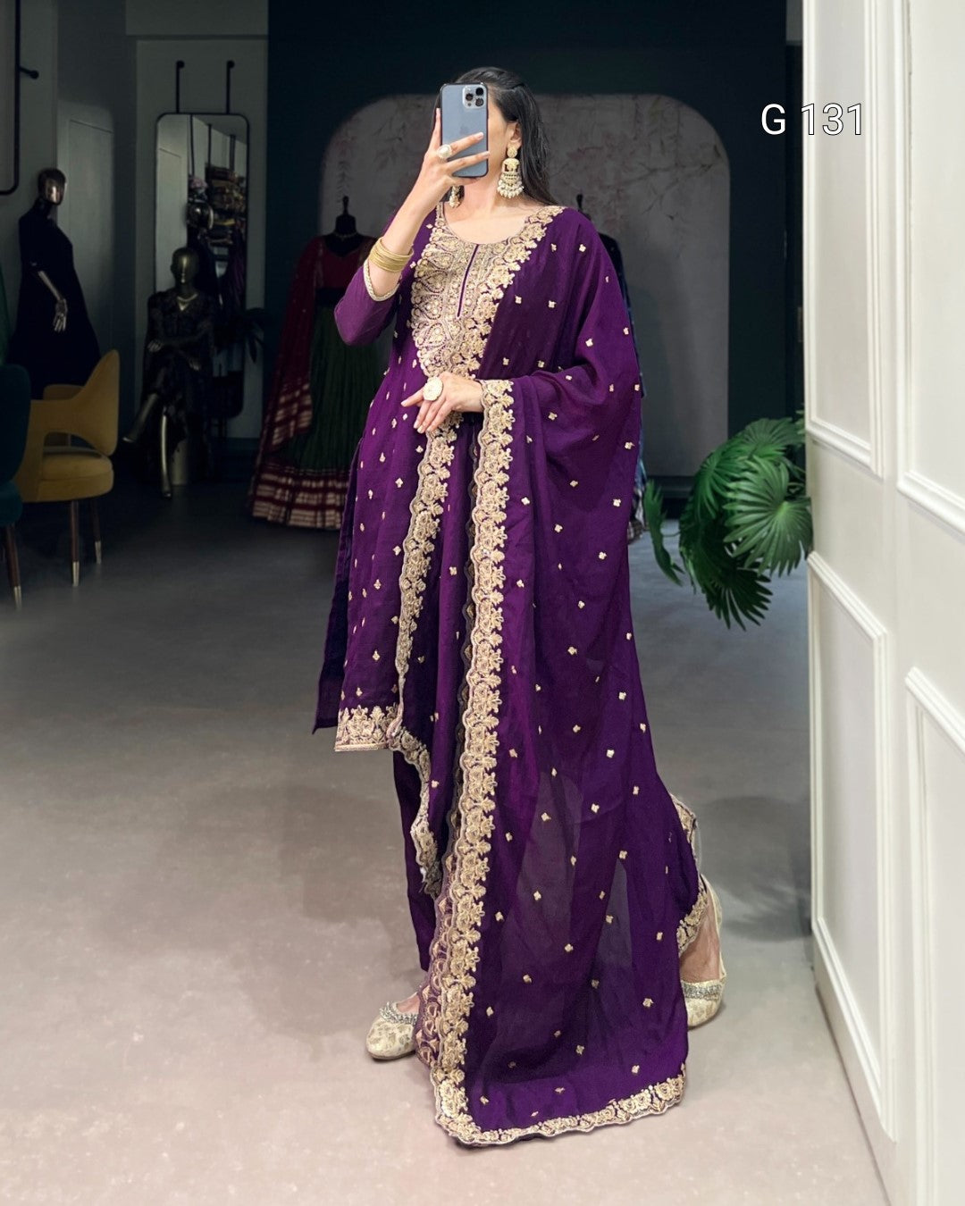 Person wearing a purple traditional outfit with gold embroidery in a room.