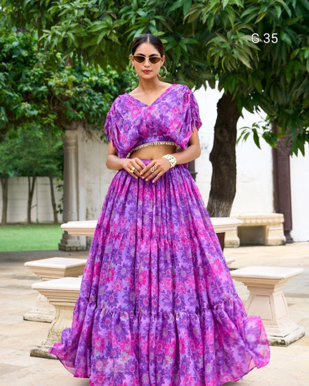 Woman wearing a purple floral dress standing outdoors with greenery in the background
