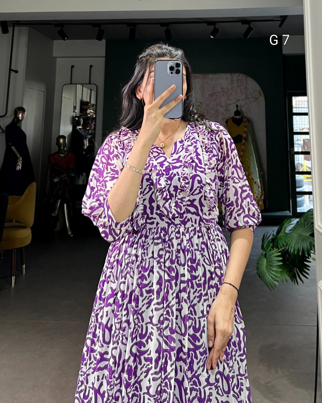 Person wearing a purple and white patterned dress taking a mirror selfie.