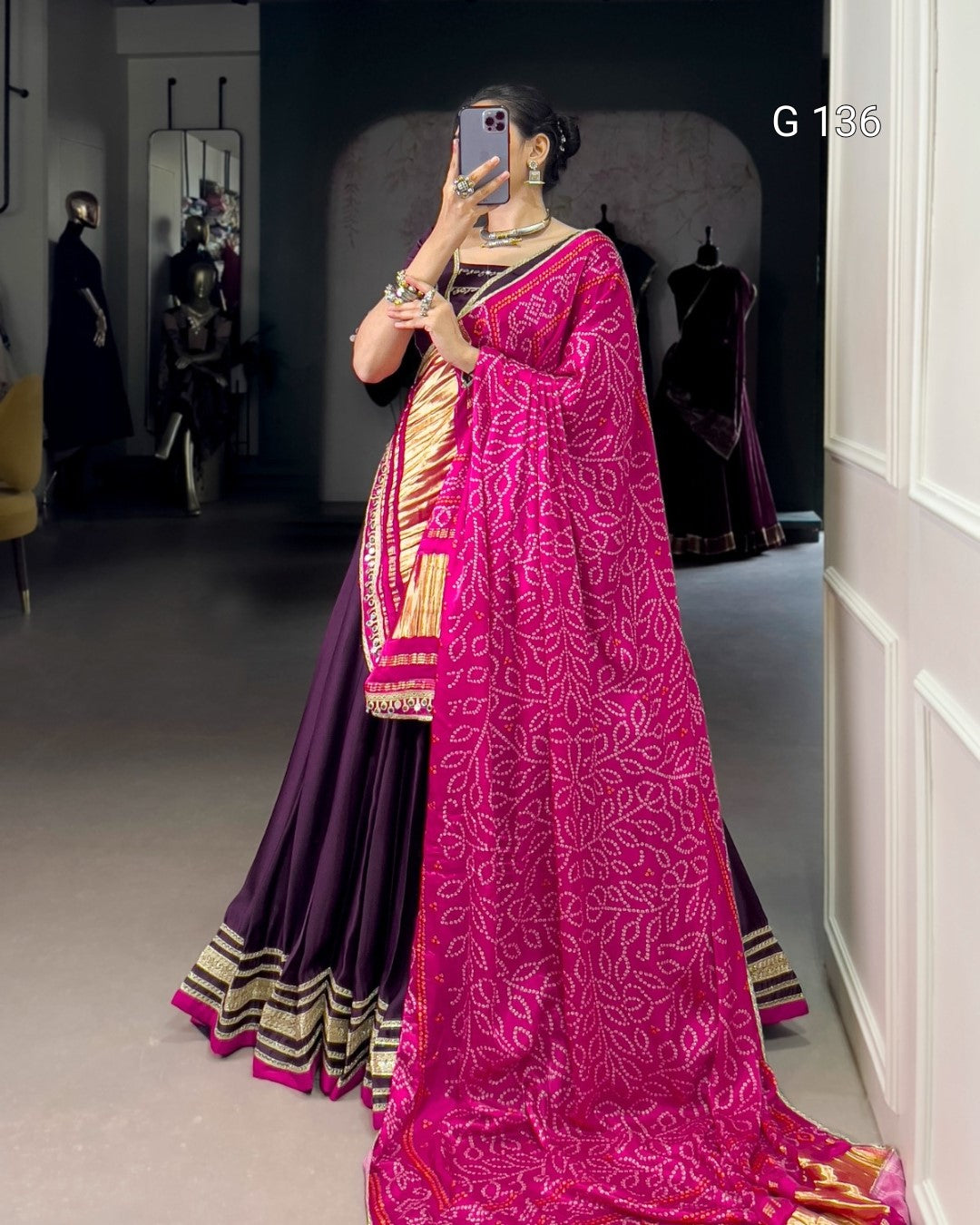 Person wearing a vibrant pink saree with a gold border, standing in a room.