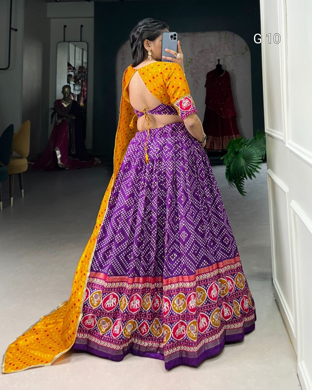 Person wearing a traditional purple and yellow saree in a room.