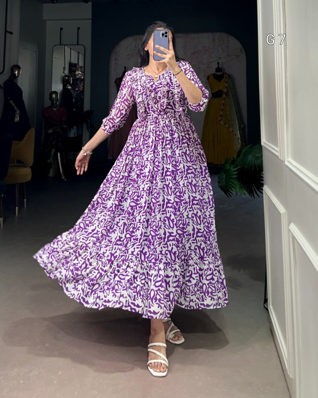 Person wearing a purple floral dress in a room with mirrors and furniture.