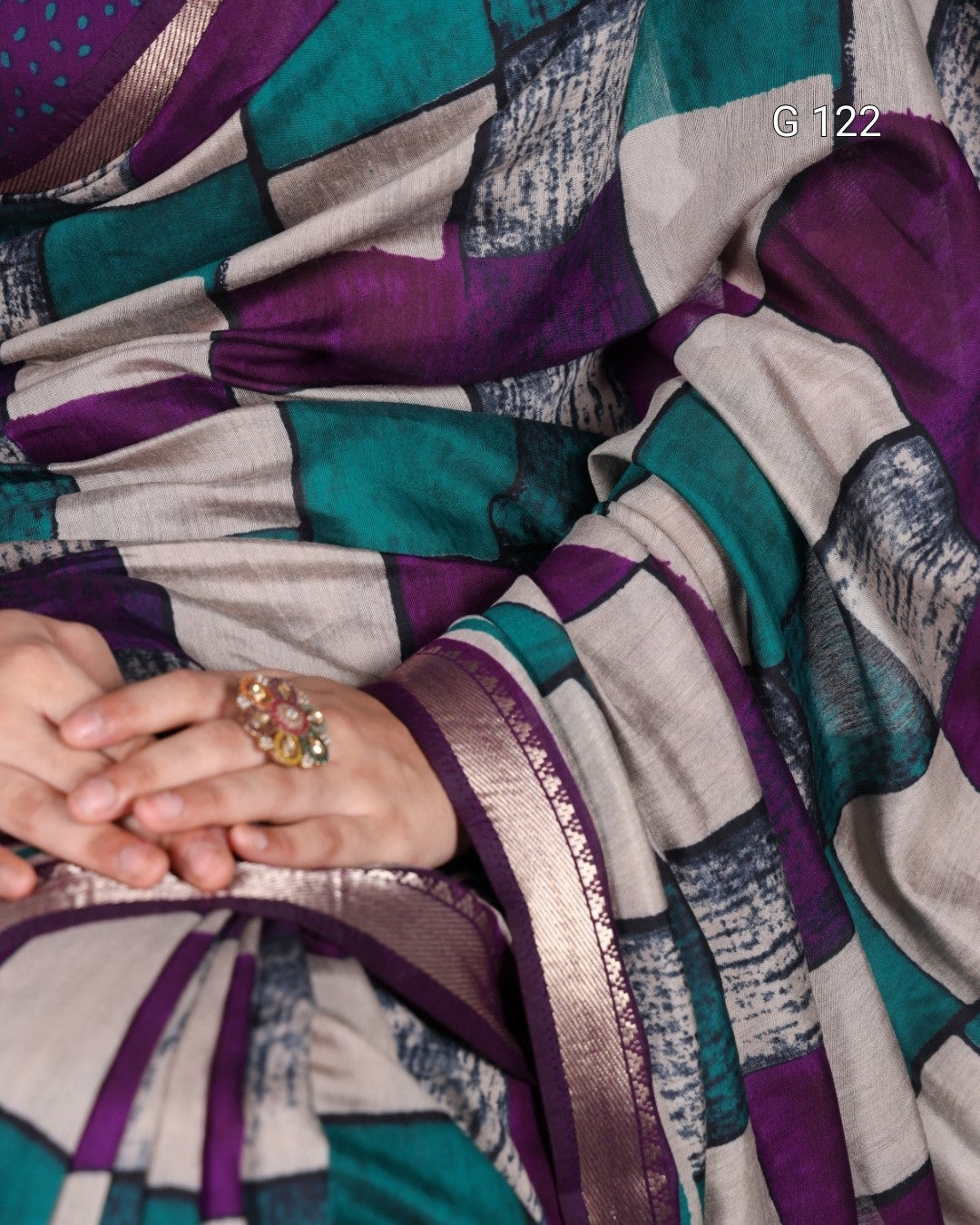 Colorful patterned fabric with a close-up of hands wearing a ring.