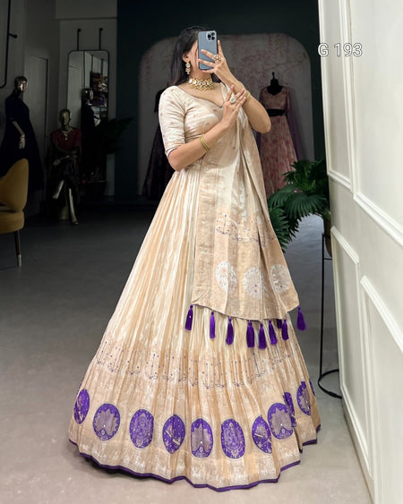 Woman wearing a beige and purple traditional outfit with tassels in a room.