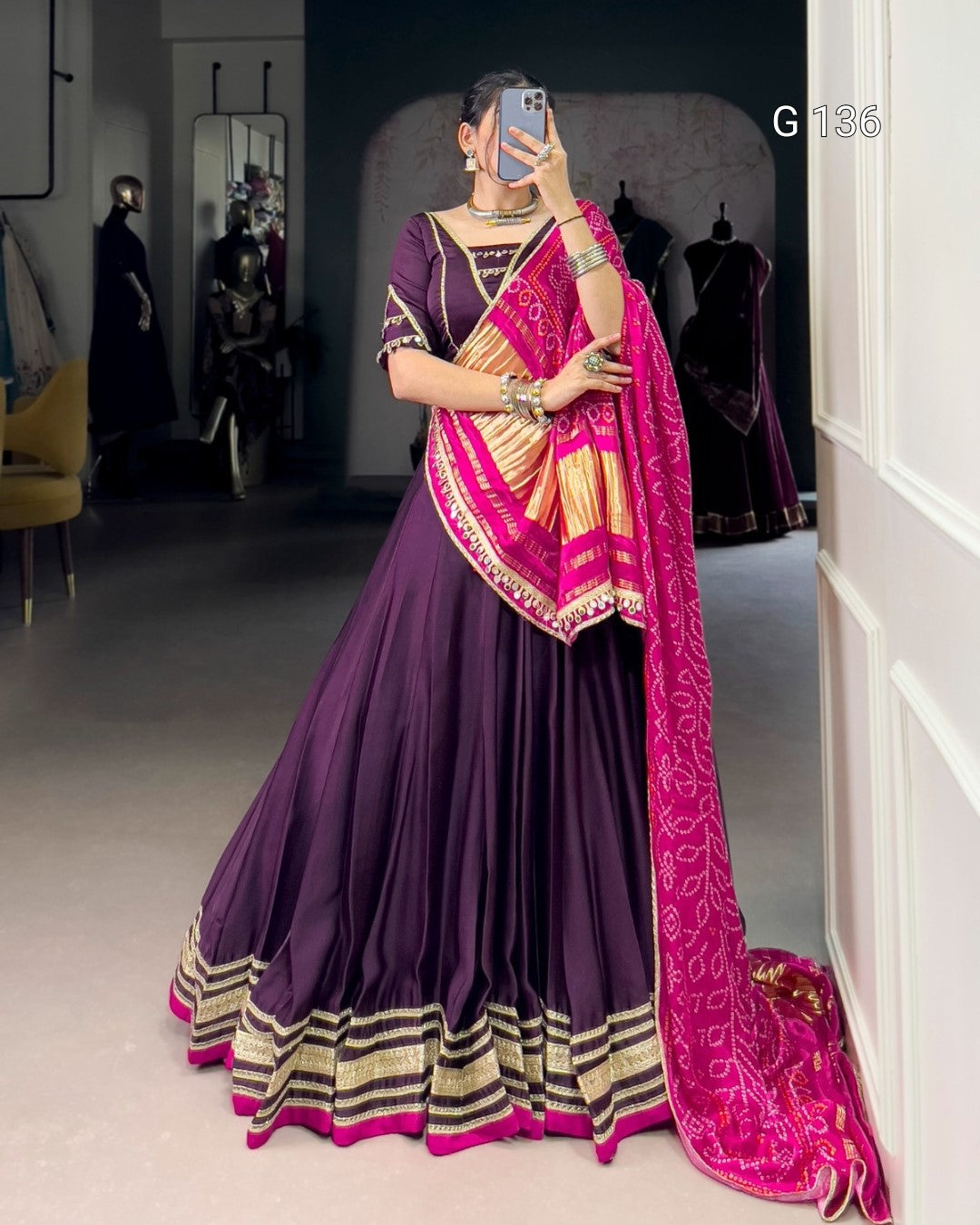 Woman wearing a traditional purple and pink saree in a room.