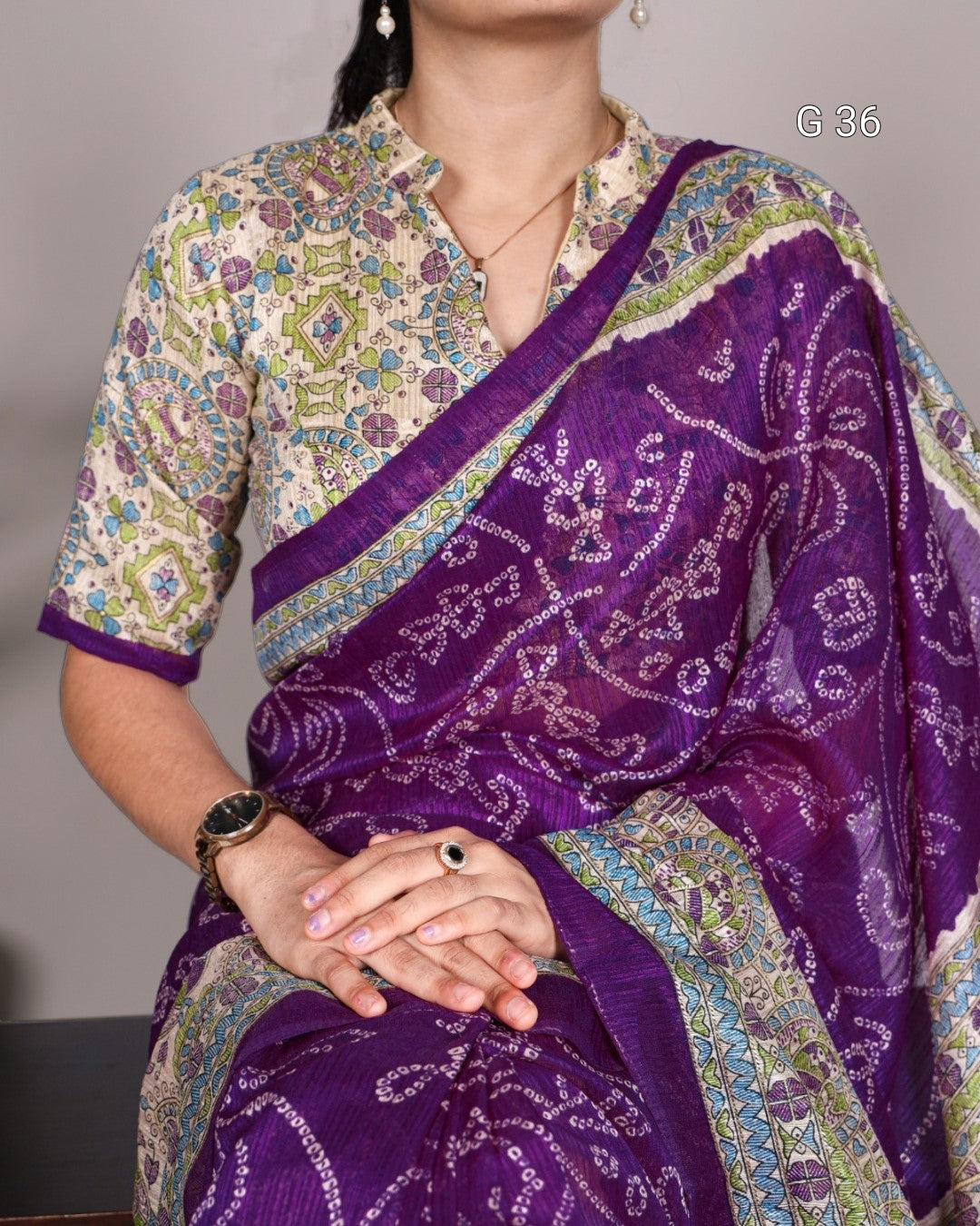 Woman wearing a purple saree with a patterned blouse against a neutral background
