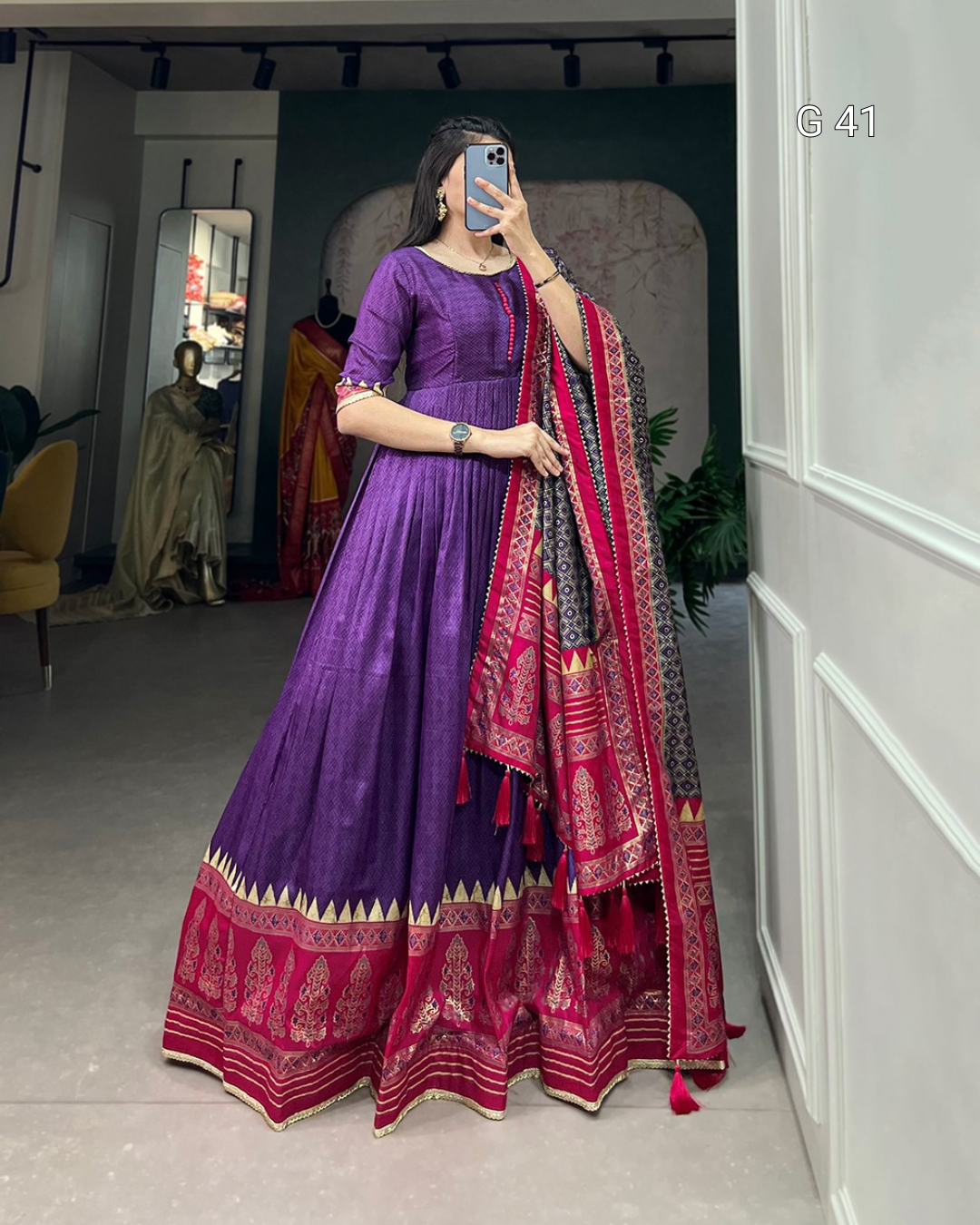 Person wearing a purple outfit with a red and gold dupatta in a room.