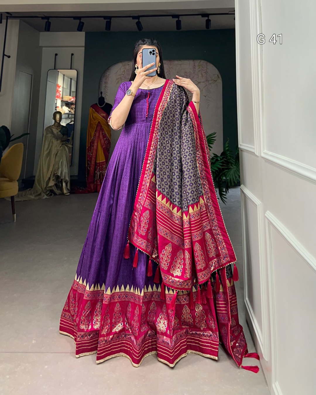 Person wearing a traditional outfit with a purple and pink saree in a room.