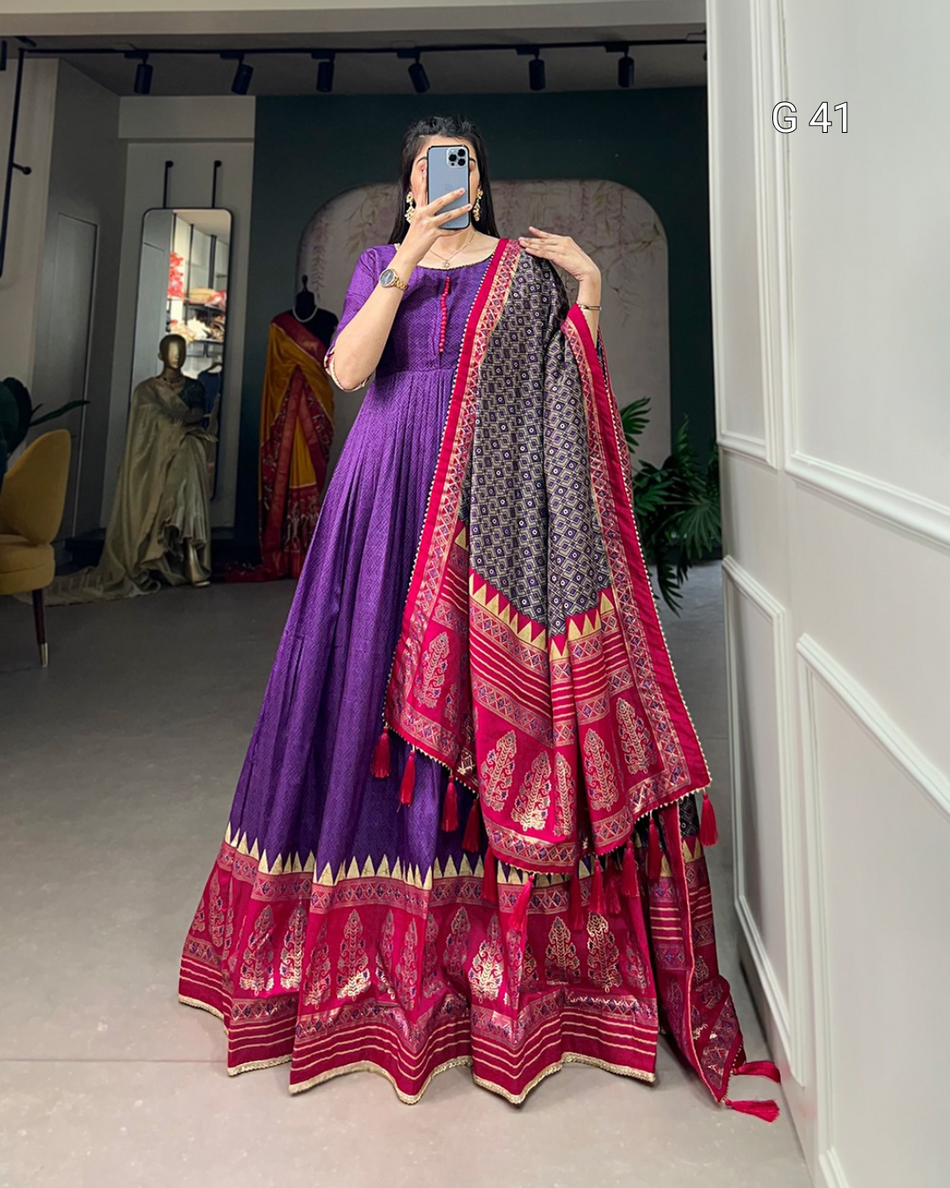 Person wearing a traditional outfit with a purple and pink saree in a room.