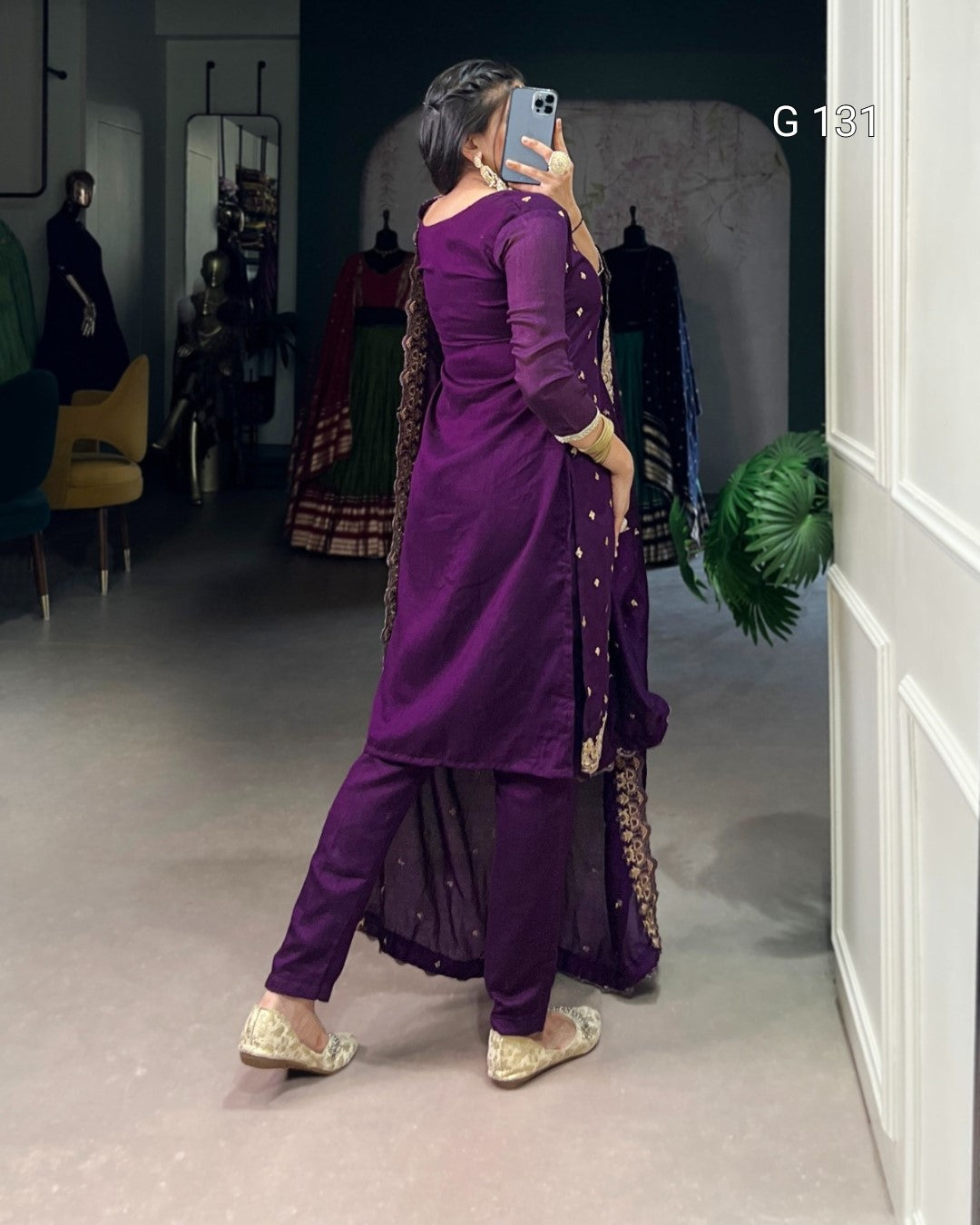 Person wearing a purple traditional outfit with gold details in a store setting.