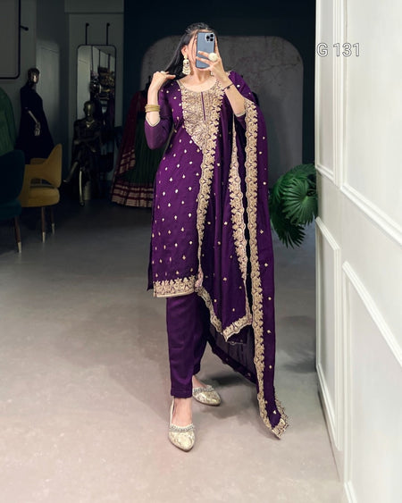 Person wearing a traditional purple outfit with gold embroidery in an indoor setting.