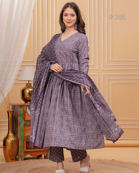 Woman wearing a purple traditional outfit with a scarf in a decorated room.
